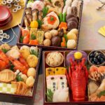 お正月のおせち料理が並ぶ華やかな三段重。海老・黒豆・栗きんとん・数の子などが彩りよく盛り付けられた和風料理の写真。