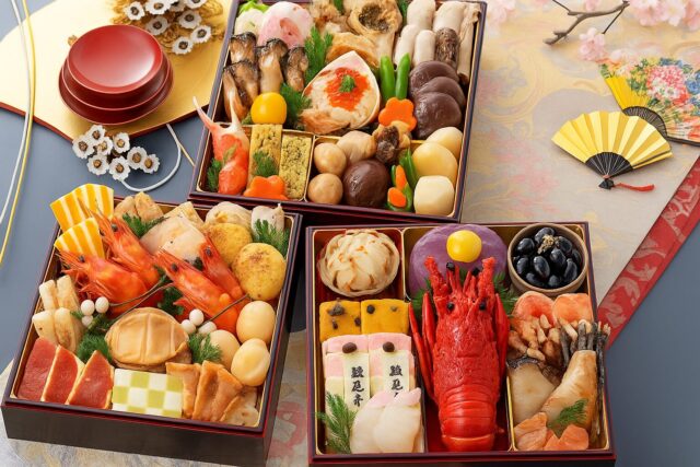 お正月のおせち料理が並ぶ華やかな三段重。海老・黒豆・栗きんとん・数の子などが彩りよく盛り付けられた和風料理の写真。