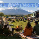 富士山の見えるキャンプ場で開催される音楽フェスの様子。テントやレジャーシートでくつろぐ参加者とライブステージの風景